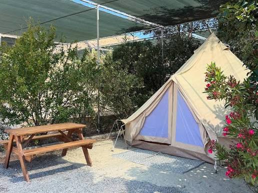 Furnished bell tent with a picnic table in a green, shaded setting